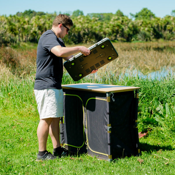 Person setting up a Zempire Stealth-Jet Wide Stove on an outdoor table on a grassy area